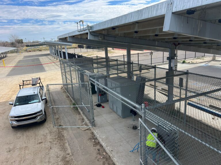 Technicians working on the solar carport structure or electrical component replacement.