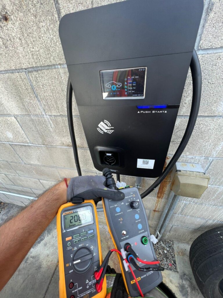 Electrician performing final wiring or inspection on an EV charging unit.